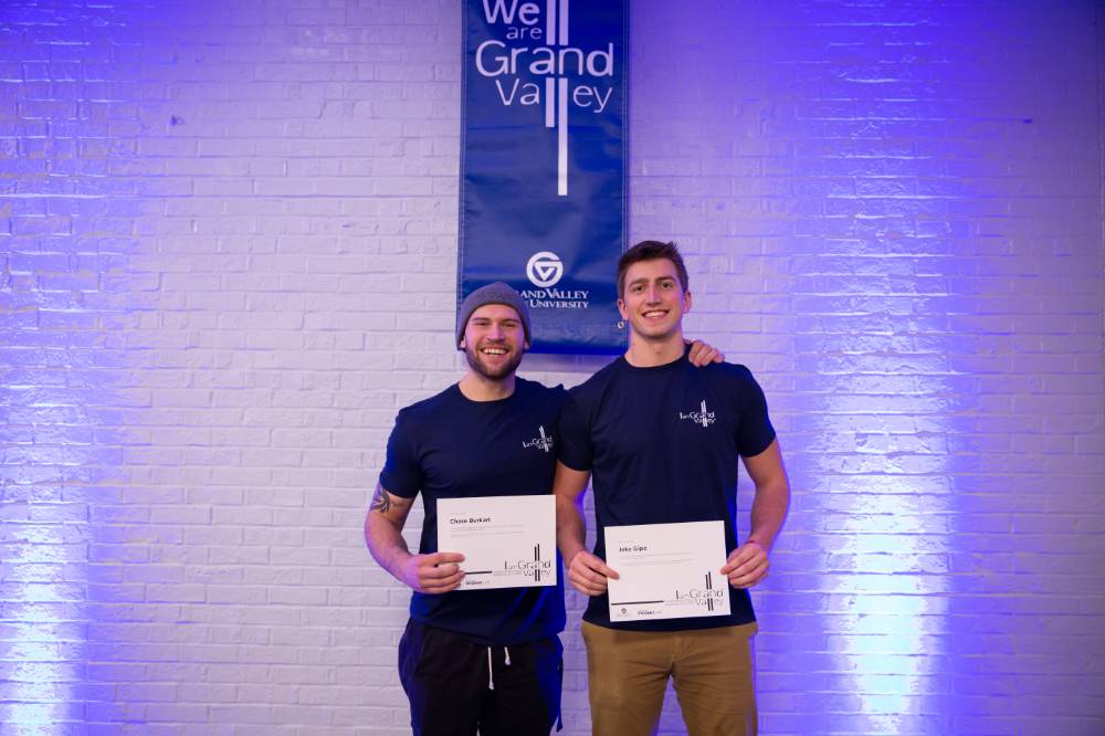 Students posing with their I am GV certificates in front of blue lights.